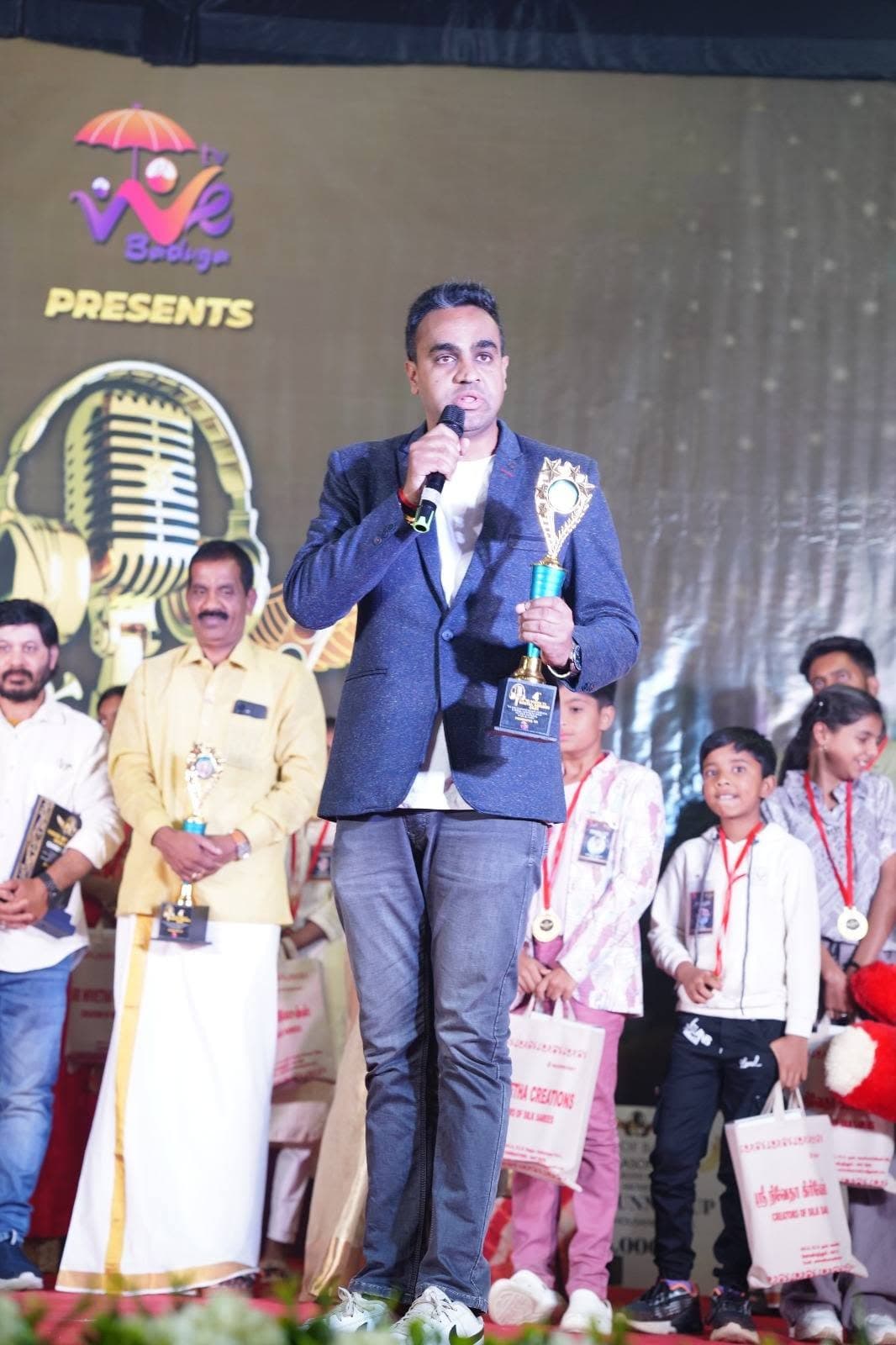 Manesh holding a trophy on stage at an award night